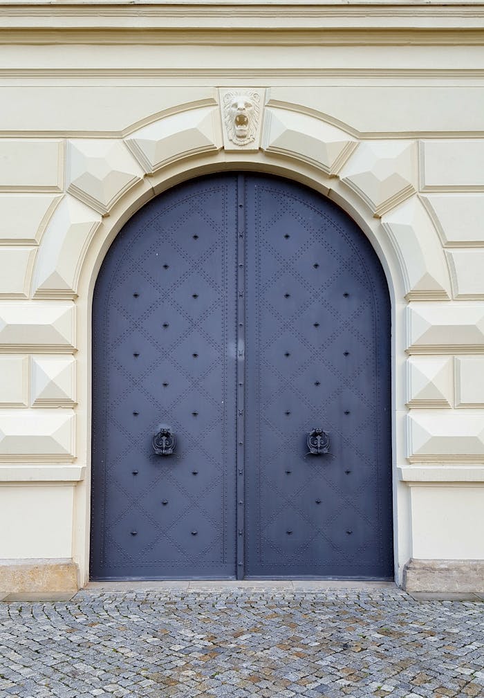 A classic and elegant arched iron doorway set in a stone building facade, showcasing architectural beauty.